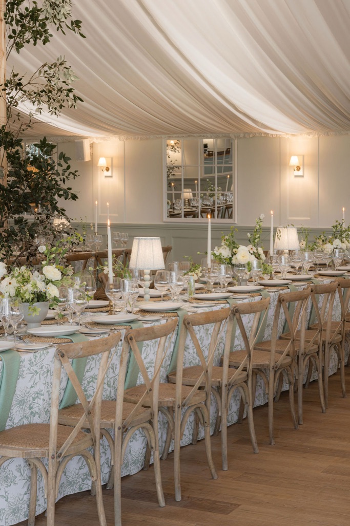 A long table laid under a draped ceiling, the lamps lit
