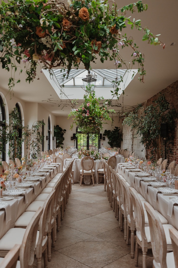 A wedding banquet laid under a hanging installation of flowers